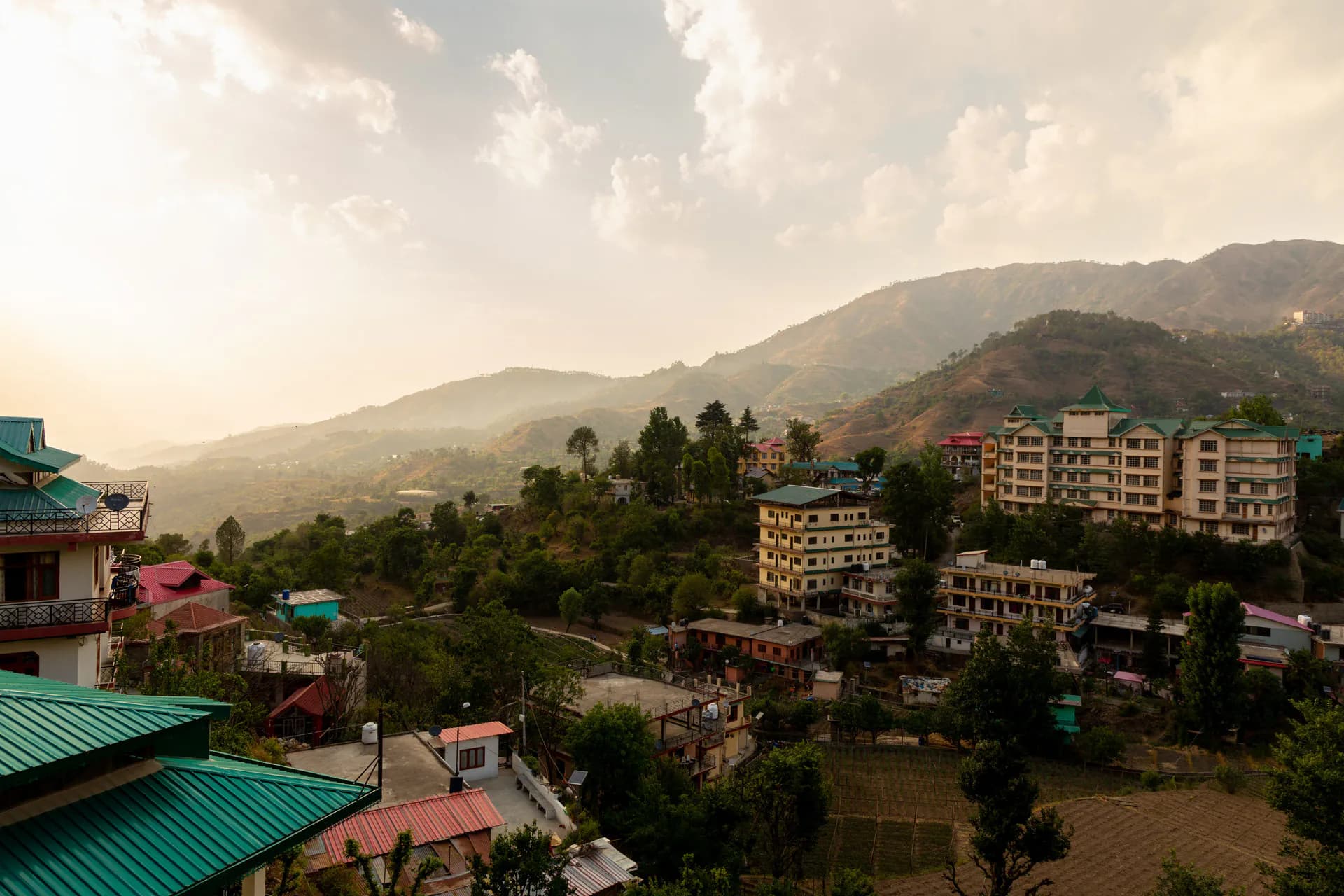 A panoramic evening view of the rolling green hills and peaceful mountain village surroundings of Mohija Homestay in Kandaghat, Himachal Pradesh
